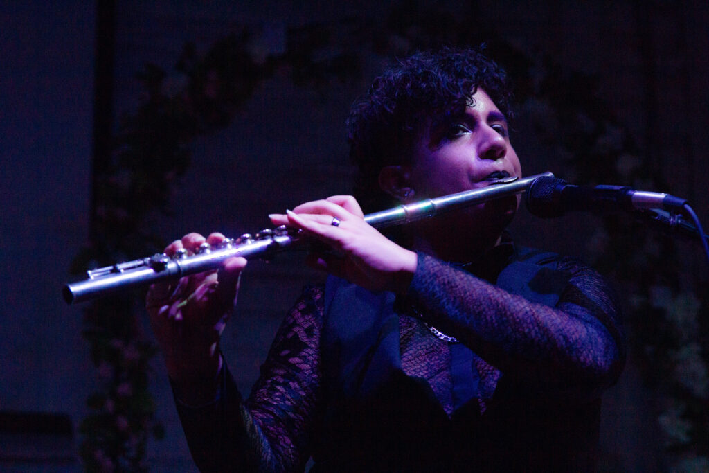 Me playing flute in a sheer black top & long vest
