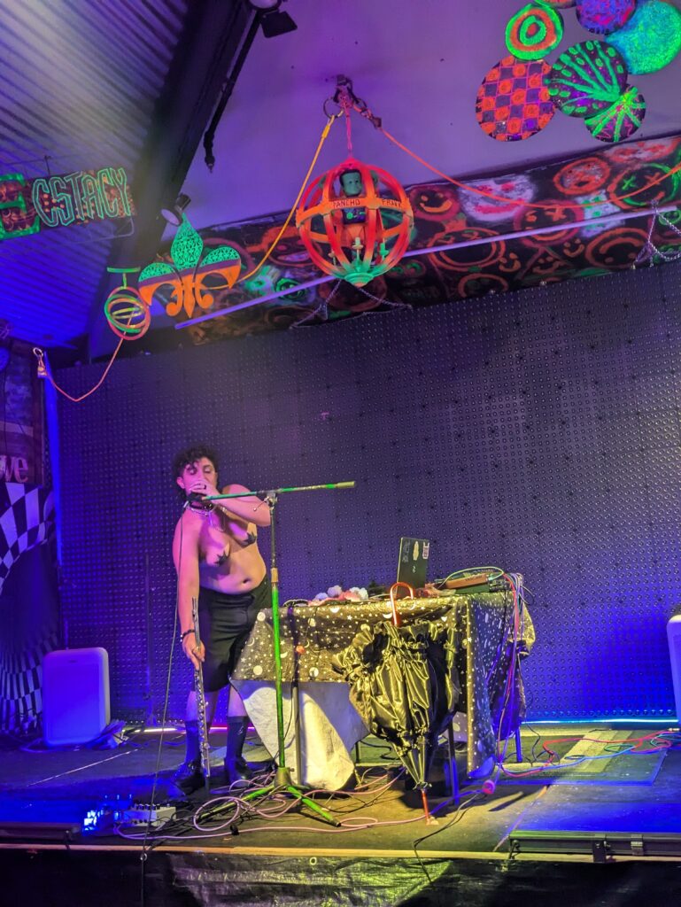 Me without a shirt on singing into a mic. The venue I'm at is filled with blacklight decorations
