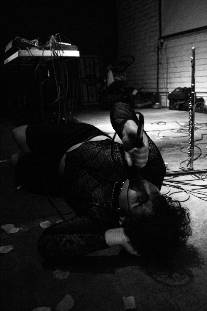 Black and white photo of me singing into a mic on a venue floor